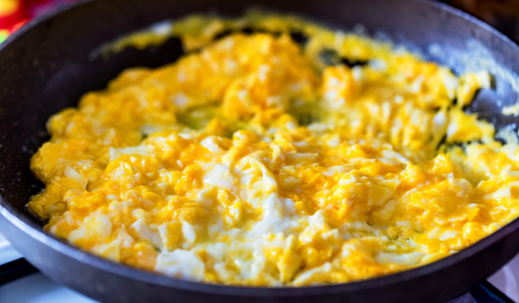 Scrambled egg in frying pan close
