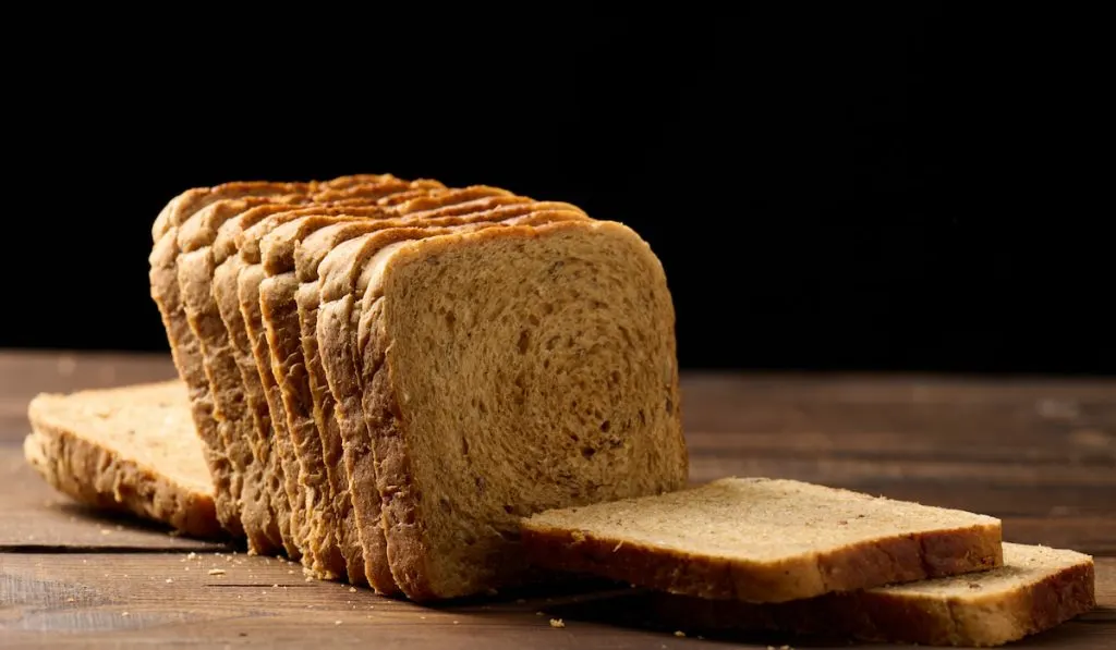 Slices of bread on a wooden table black background 