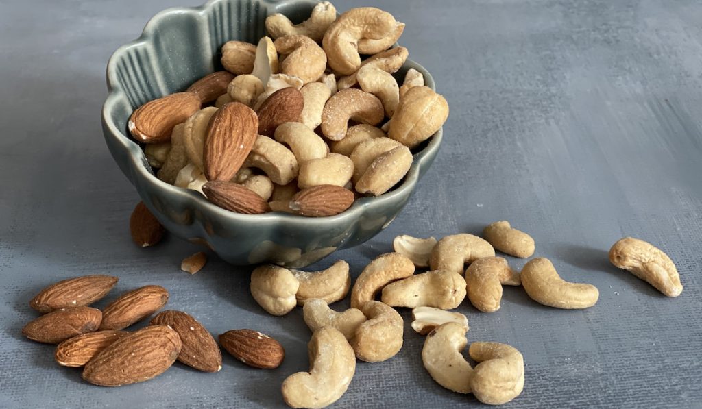 almonds and cashew nuts in a bowl on gray background 