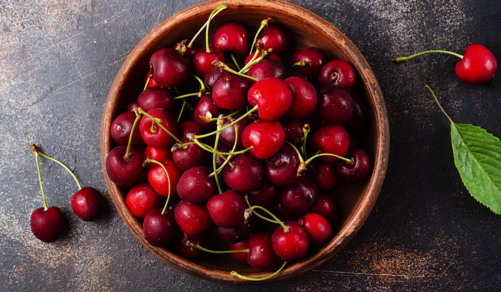 cherries in a wooden bowl with leaf 