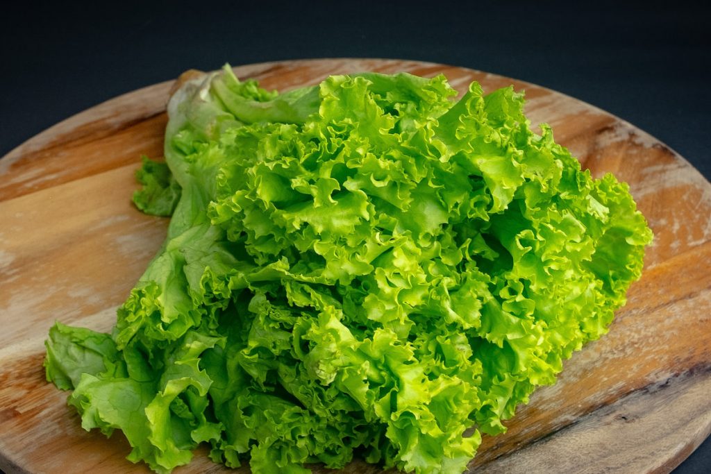 fresh lettuce on wooden round chopping board 