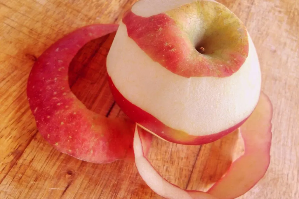 peeling red apple on wooden table