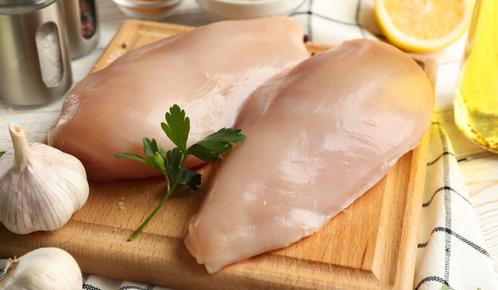 raw chicken meat on wooden chopping board 