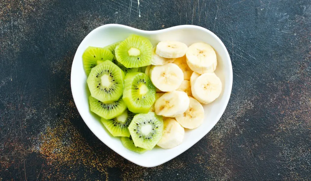 slices of banana and kiwi on a heart shaped bowl 