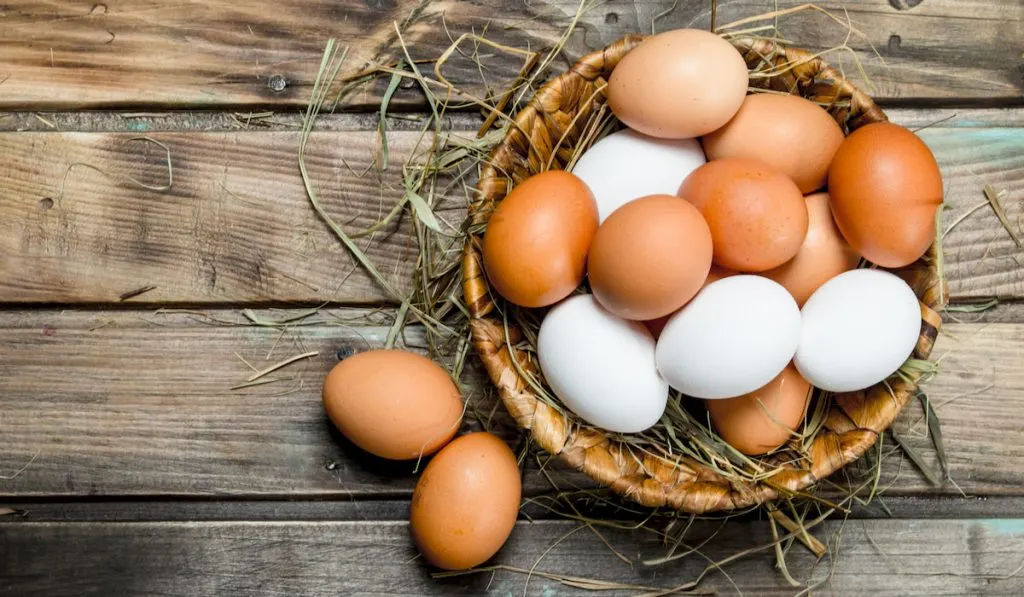 white and brown eggs in a basket on wooden table